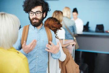 One of passengers discussing something with young woman while waiting for flight registration in check-in counter