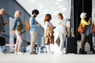 Several passengers standing in queue while waiting for check-in registration before flight
