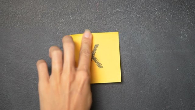 Closeup woman's hand sticking note with letter "X" on the blackboard - video in slow motion