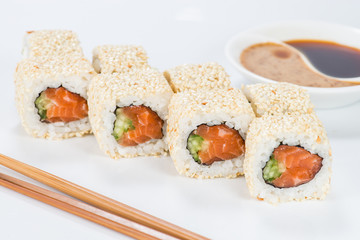 Delicious sushi rolls with rice, cream cheese, cucumber and sesame seeds on light background