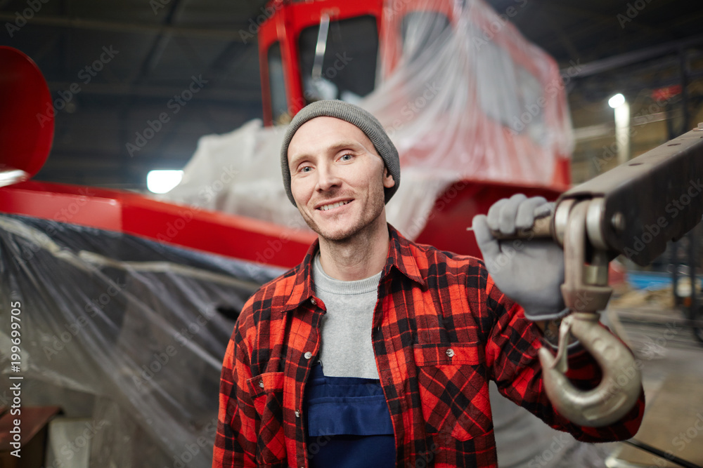 Wall mural young smiling man in workwear looking at camera during working day at modern shipbuilding factory