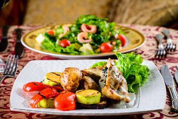 Romantic dinner at a restaurant. Two appetizing dishes with shrimp and baked vegetables and glasses with wine