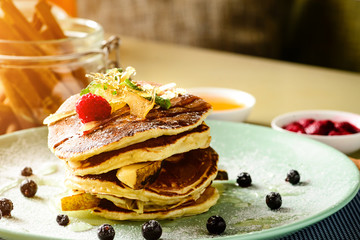 Sweet delicious pancake blinis with jam and berries in the plate in rays of the sun. New restaurant menu for the holiday Maslenitsa