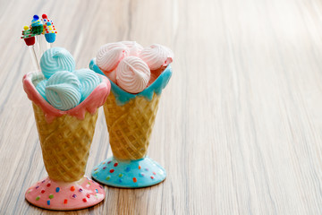 blue and pink meringue in the pink and blue cones with cupcakes on wood background or happy mothers...