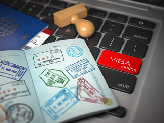 Visa online application concept. Opened passport with visa stamps with airline boarding pass tickets and stamper on the computer keyboard.