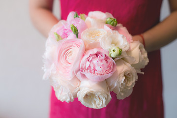A woman in a pink dress is holding amazing bridal bouquet of pink peonies Sarah Bernhardt, ranunculuses Hanoi, Keira roses and white Eustoma. Wedding floristry
