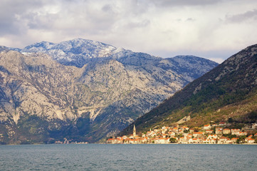 Fototapeta na wymiar Cloudy Mediterranean landscape with sunny seaside city. Montenegro, view of Bay of Kotor and ancient town of Perast on spring day
