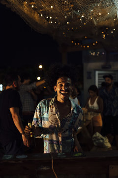 DJ dancing with bottle of beer in an outdoor party at night