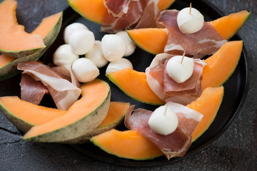 Close-up of prosciutto ham and mozzarella balls with cantaloupe melon, horizontal shot