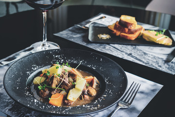 Romantic dinner in the resraurant. Two appetizing dishes and glass of red wine, toned image