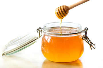 Sweet honey in jar with honey wooden spoon on light background