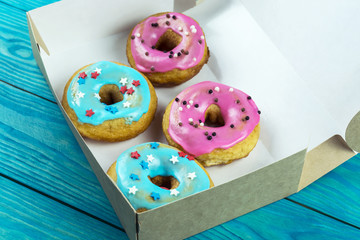 Multicolored homemade donuts in a box on a wooden background