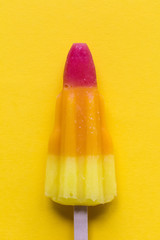 Rocket shaped summer ice lolly on a bright yellow background