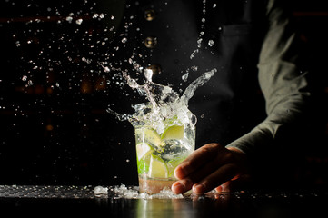 Cocktail splash with ice cubes and lime