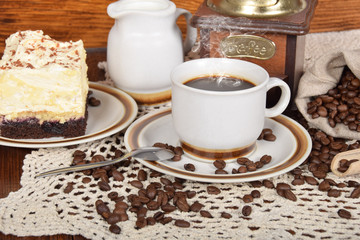 cake with cream and coffee in a beige cup with a jug full of milk