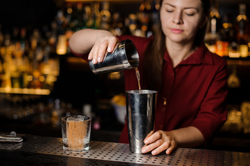 Female bartender making cocktail at the bar counter