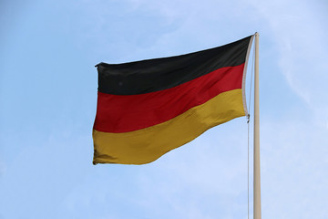 Tri Color of German Flag, black red and yellow color on blue sky background. Blown away by wind.