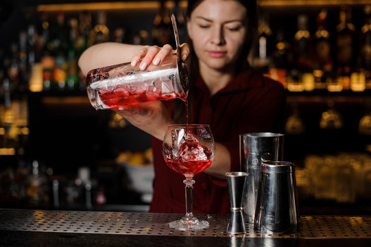 Bartender girl making a fresh light red cocktail