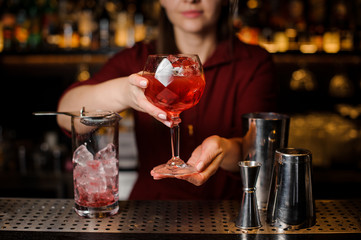 Bartender girl serving a red campari cocktail