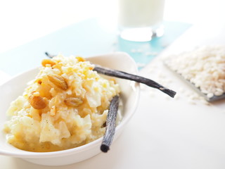 Creamy vanilla rice pudding with rice and milk on white and blue background