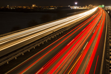 Night scene of motion blurred light tracks glowing to the darkness of highway traffic to the city...