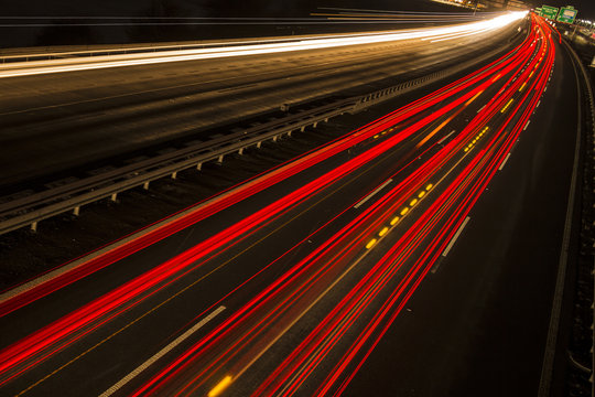 Night scene of motion blurred light tracks glowing to the darkness of highway traffic to the city just after sunset. Creative long time exposure diagonal composed photography. © Martin