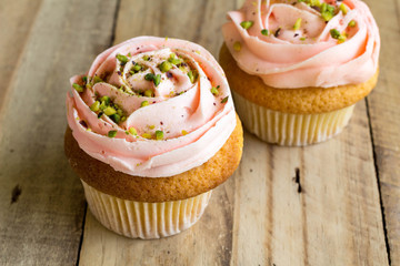 Two pink cup cakes on rustic wooden table close up