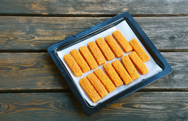 frozen fish sticks in Tray for oven on wooden background