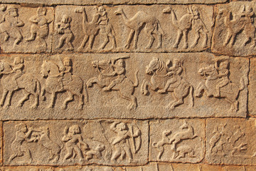 Stone bas-reliefs on the walls in Temples Hampi. Carving stone ancient background. Carved figures made of stone. Unesco World Heritage Site. Karnataka, India. Beige background.