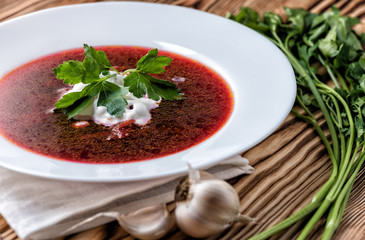Borscht on a wooden table with garlic