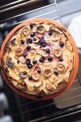 Raw vegan sweet tart, pie or cake with blueberries currants, coconut, dates, bananas, oil, cocoa powder and cashew cream on a silicone plate in the oven . Organic product.