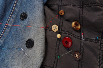 Accessories for sewing on the background of cotton and jeans clothes close up