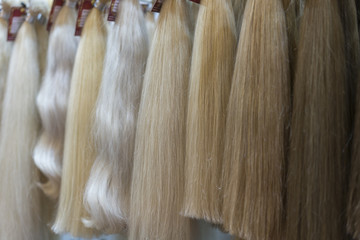 Close up brown, white and another color of hair wigs display in beauty salon.