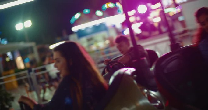Teenage friends crashing at bumper cars ride at amusement park