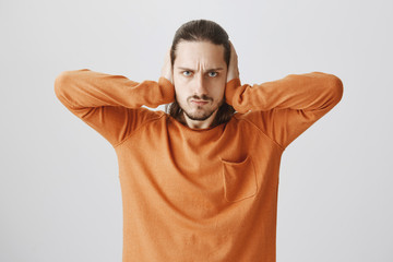 Enough of listening uninteresting talks. Attractive annoyed guy with beard covering ears with palms...