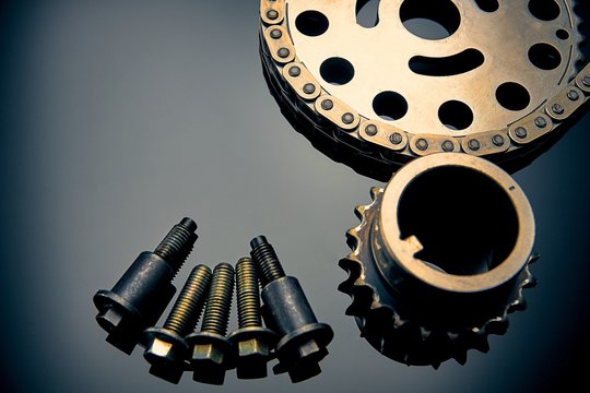 Roller chain with sprocket on dark background. It is used on cars, motorcycles, bicycles and in mechanical engineering.