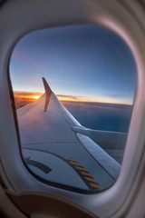Airplane wing through window during a vibrant sunset