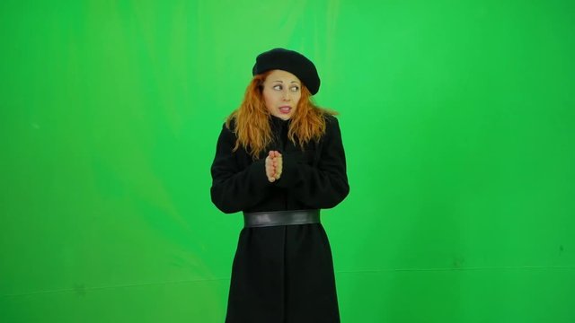 Elegant red hair woman in long black coat and beret frozen from cold wind green-screen 50fps