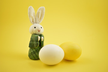 White rabbit toy stock images. Easter bunny on a yellow background. Easter rabbit with egg. Spring decoration images. Easter concept