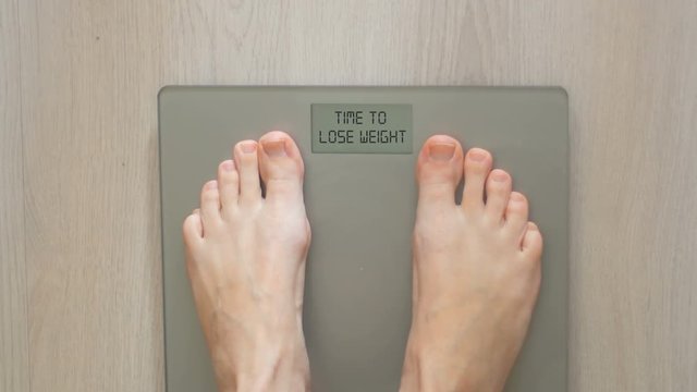Woman on scale. Display showing "Time to lose weight" Concept: Lose weight