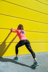 young woman stretching on a wall