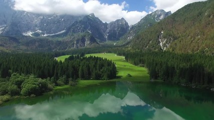 AERIAL VIEW: flight over Lake Fusine in Italy .North face of Mangart. camera moves backwards