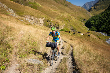 Biker pushes his bicycle up in high Caucasus mountains