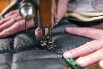 Sewing process of the leather belt. old Man's hands behind sewing. Leather workshop. textile vintage sewing industrial
