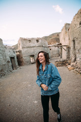 Portrait of an attractive young woman posing close to vintage village. Lifestyle and fashion concept