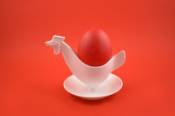 Vintage white plastic chicken egg cup holder with red egg stock photo images. Retro chicken egg cup holder on a red background stock photo. Easter egg on a red background
