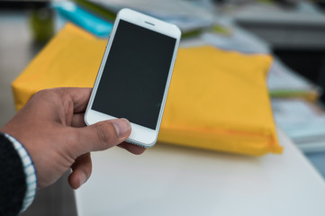 Closeup view of a man's hand online working on smart phone with blank display background over light indoors interior. Using internet digital device as modern design communication technology lifestyle