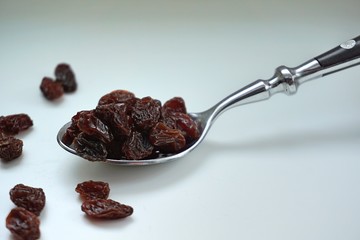 raisins. iron spoon. White background.