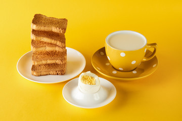 Healthy breakfast with flying toasts, cup of fresh milk with chicken egg on yellow background. Levitation food, diet, vegetarian food concept.