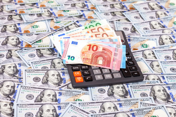 Euro banknotes and calculator on dollars background